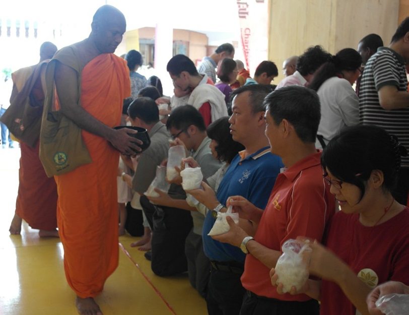 信众恭敬虔诚地献上饮食和供品，僧人托钵接受信众的供养。